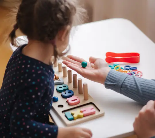 Little girl play in educational game for children with mom. Wooden game with different colors and numbers. Interactive game for clever kids. 